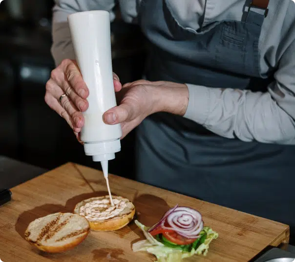 image of a person squeezing sauce onto a burger