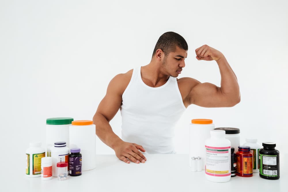 image of a man flexing over supplement bottles