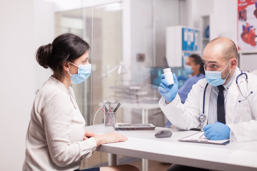 Image of a doctor holding pill bottles in front of a woman