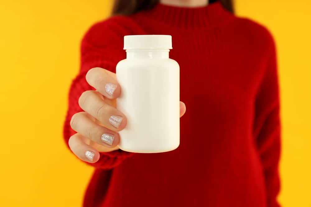 Image of a woman holding a pill bottle in hand