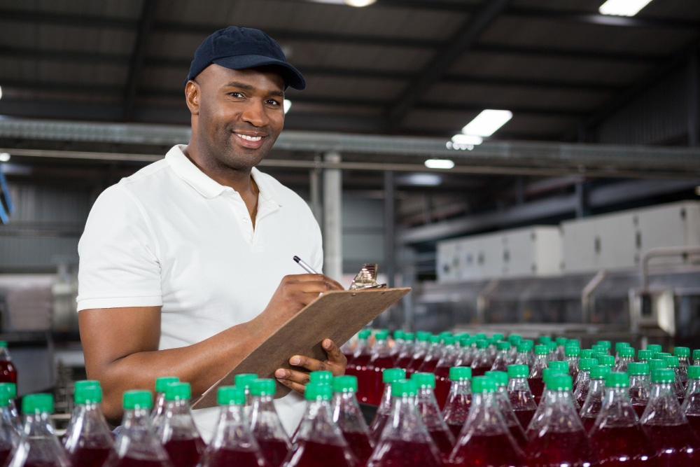 A man writing some notes over some plastic water bottles in production