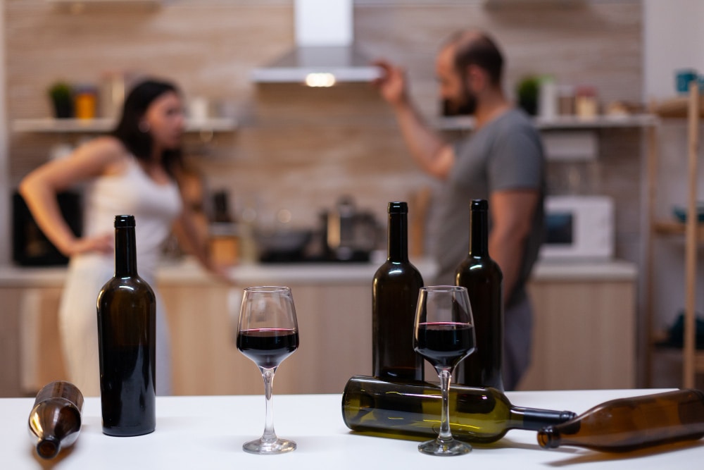 Blurred image of a couple along with plastic wine bottles in a table