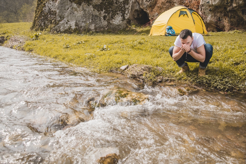 Image of a man drinking water from a river