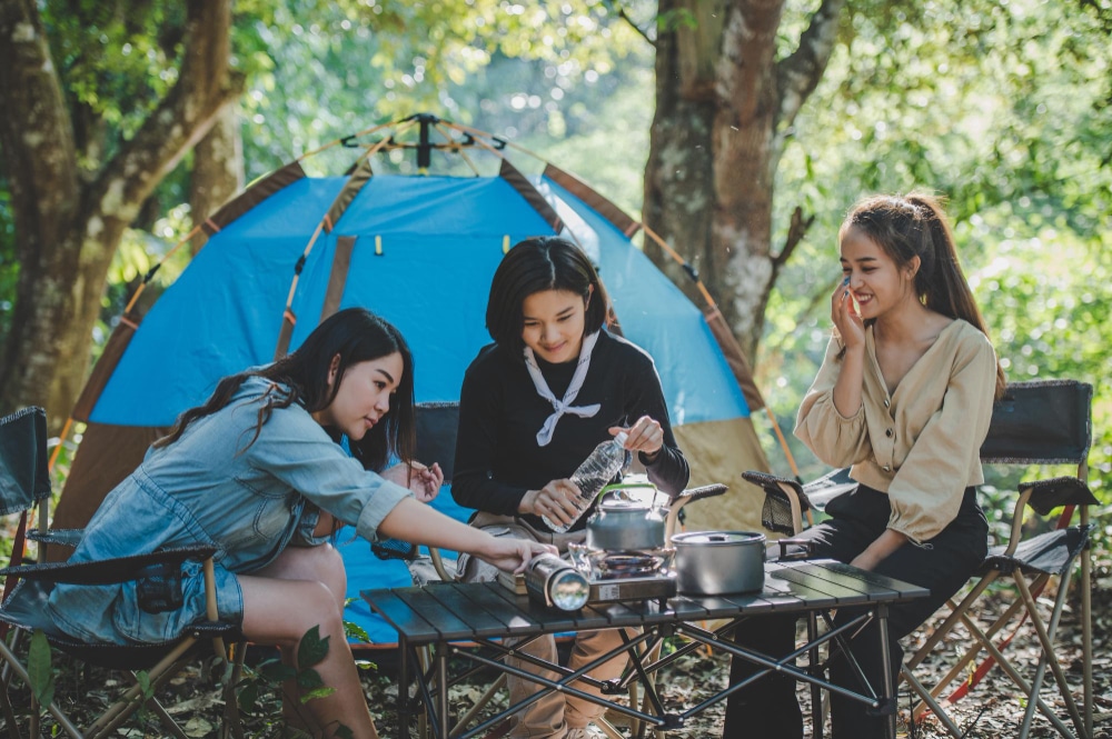 Image of three girls sitting with plastic water bottles and some food in hand.