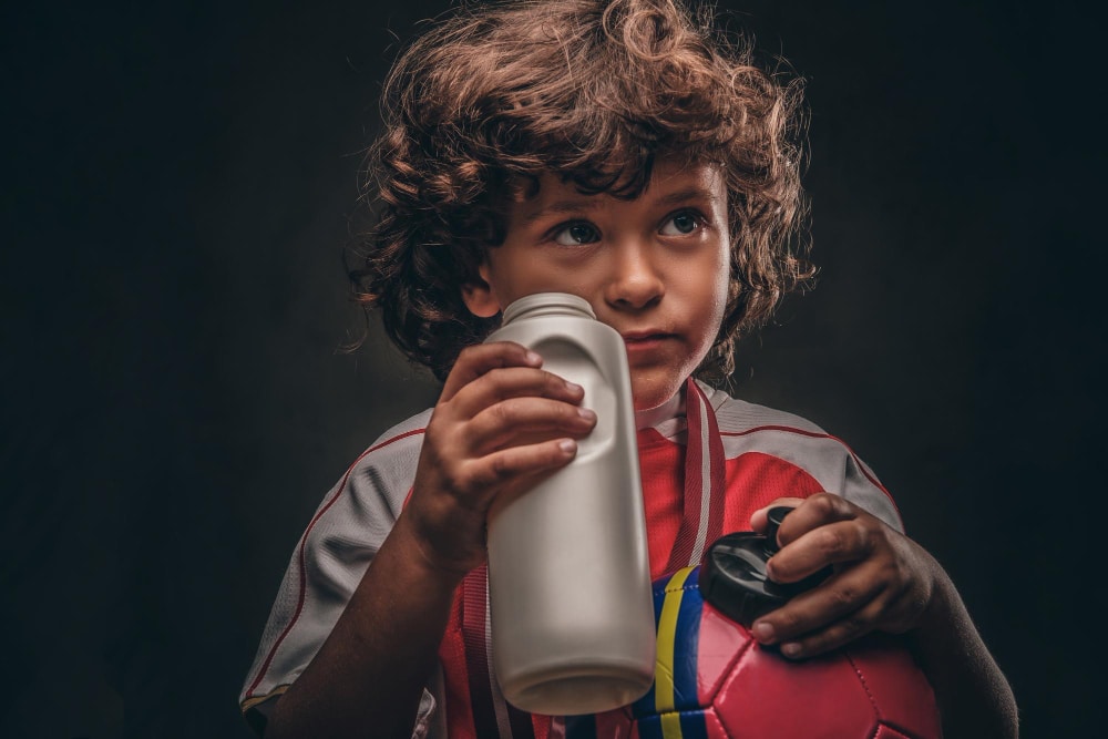 Image of a boy taking a sip from plastic water bottle.