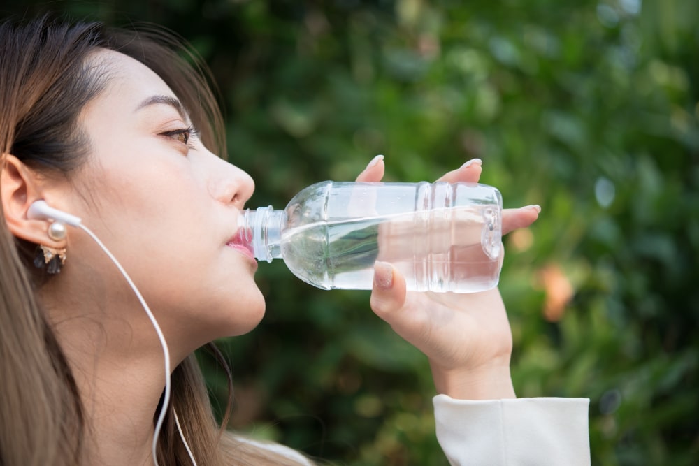 image of a woman drinking water from a disposable water bottle