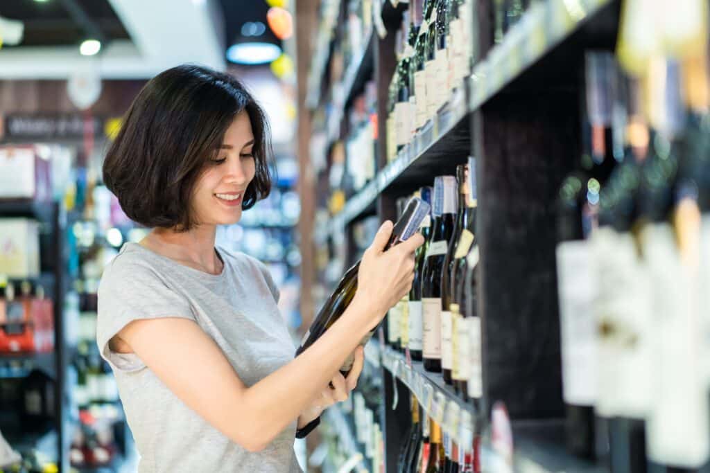 Image of a girl checking shelves of wine bottles 