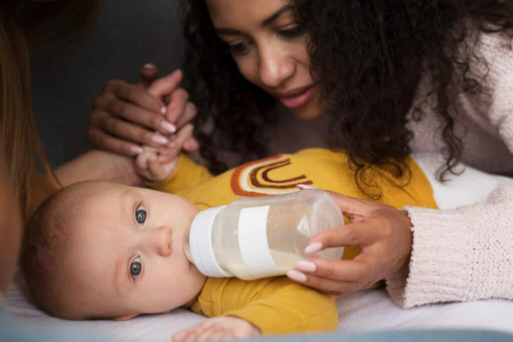 An image of a mother feeding an infant with a pp bottle