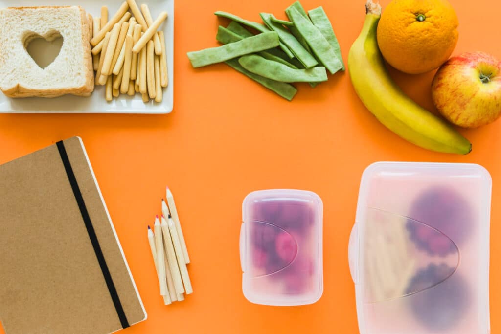 image of notebooks and pencils near plastic takeout containers