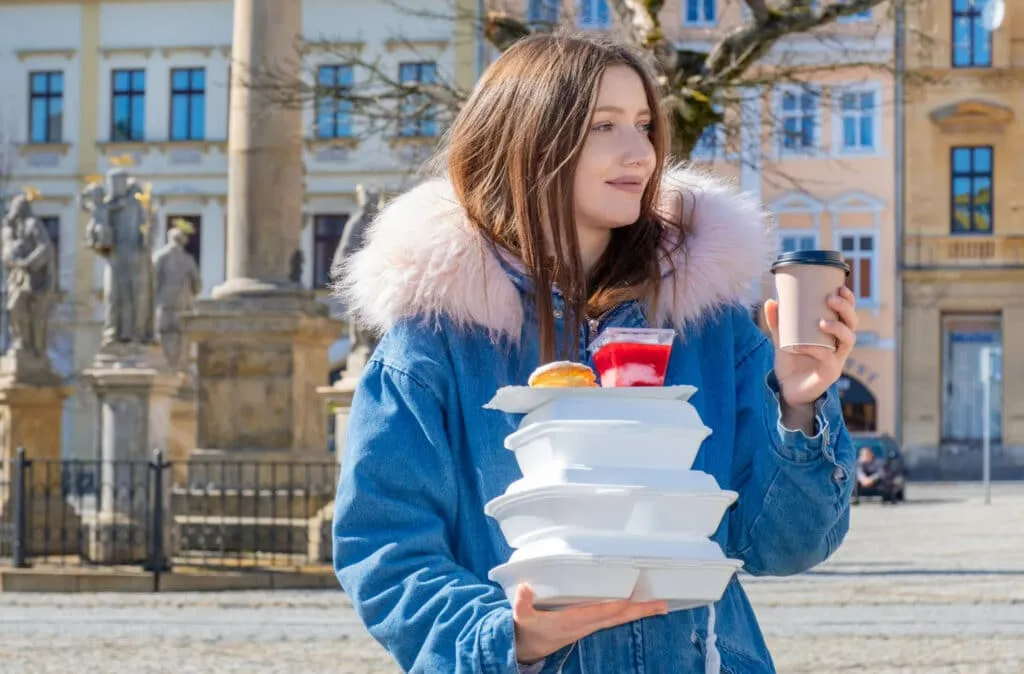 Image of a girl holding plastic takeout containers in hand
