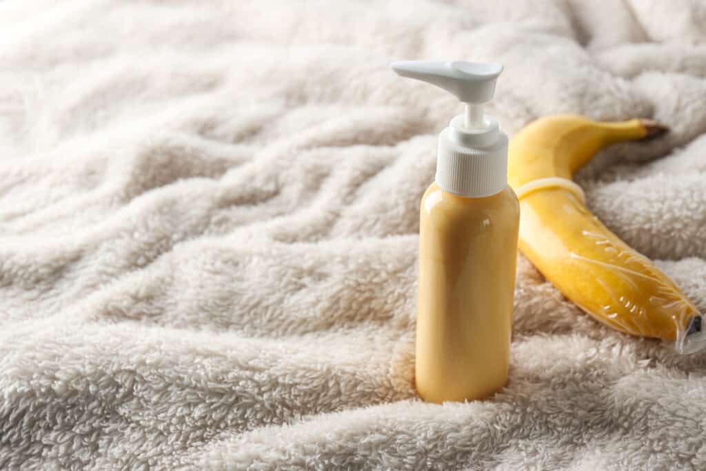 an image of a big bottle of lubricant near a condom wrapped banana