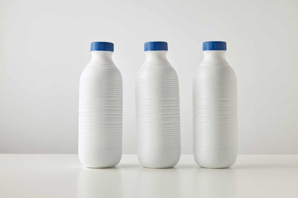Three blank white 16 oz plastic bottles with blue caps in row isolated on table in center Space for your text Merchandise retail set, rich texture