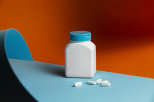 one white bottle from a Wholesale pill bottles on a blue surface in an orange background