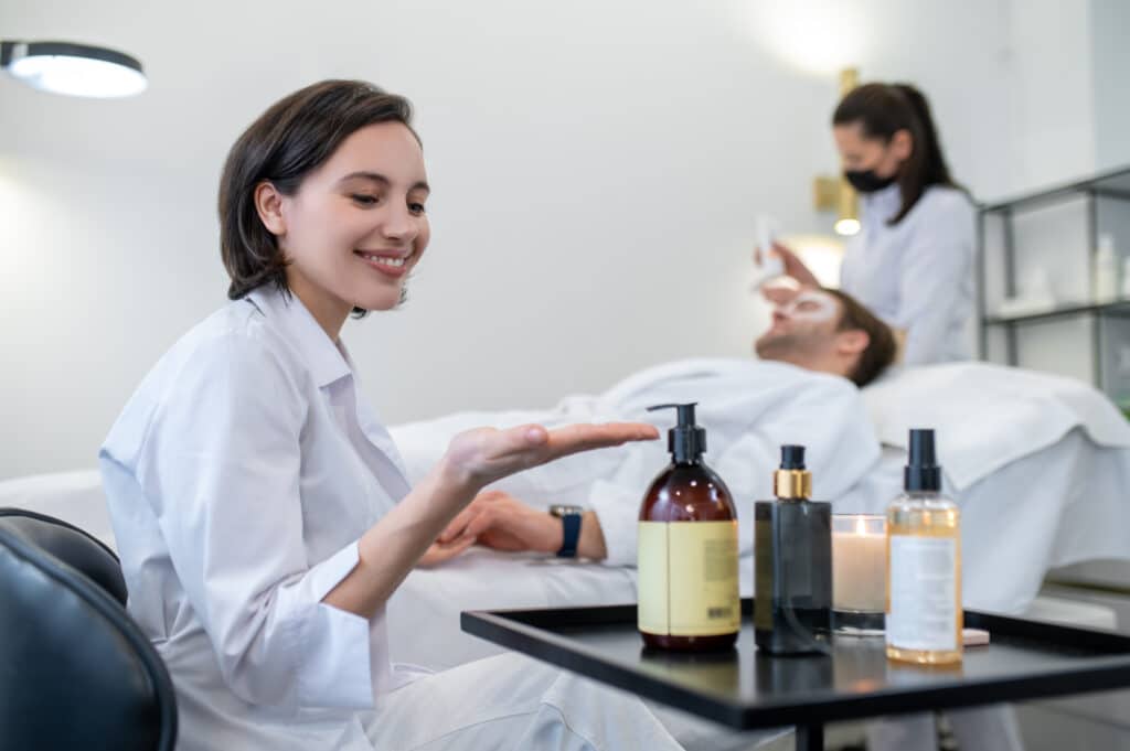 Spa salon. Cosmetologist working with the client in a spa salon using wholesale lotion bottles 