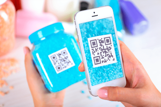 A person scanning QR code on blue jar displayed on the cosmetic packaging - via a smartphone.