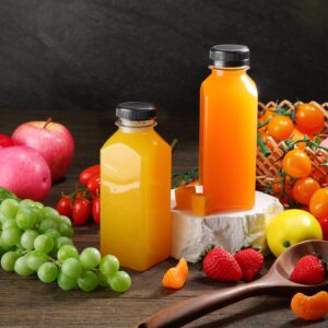 Two plastic juice containers filled with fresh juice, surrounded by fruits and vegetables.