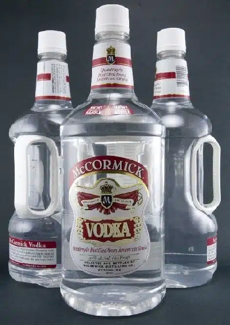 Three large plastic bottles of McCormick Vodka on a surface.

