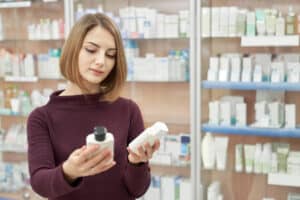 A woman comparing two cosmetic bottles at a store.