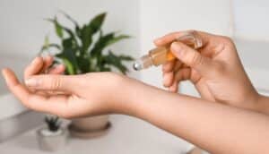 Someone trying to apply essential oil in a roll-on bottle to a hand.