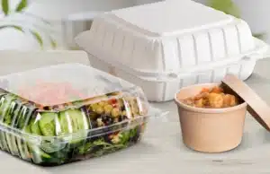 Food packaged in plastic containers, including a salad in a clear container and a takeout container.