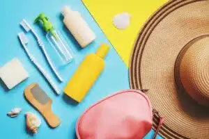 Travel size toiletries kit with sunscreen, comb, and toothbrush on a colorful background