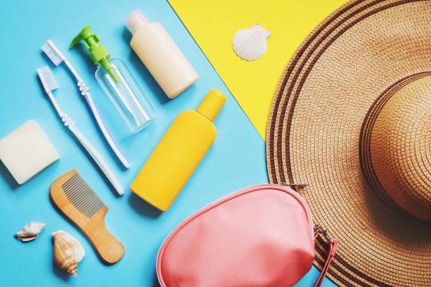 Travel size toiletries kit with sunscreen, comb, and toothbrush on a colorful background