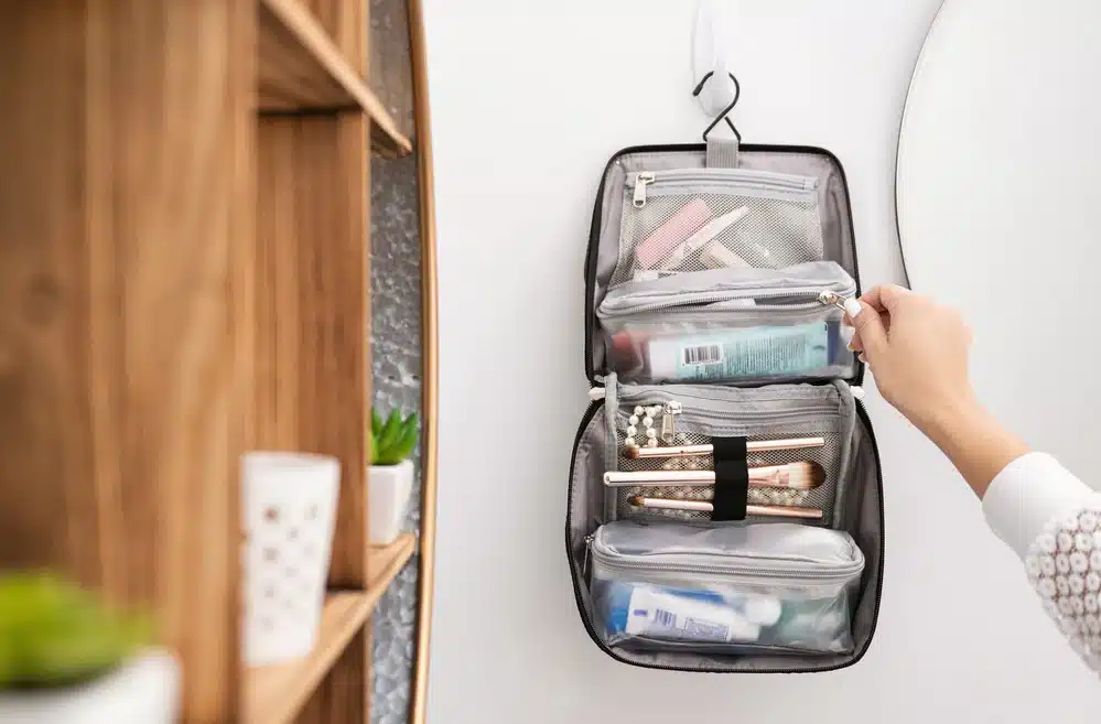 A woman packing her travel size toiletries kit in a hanging toiletry bag