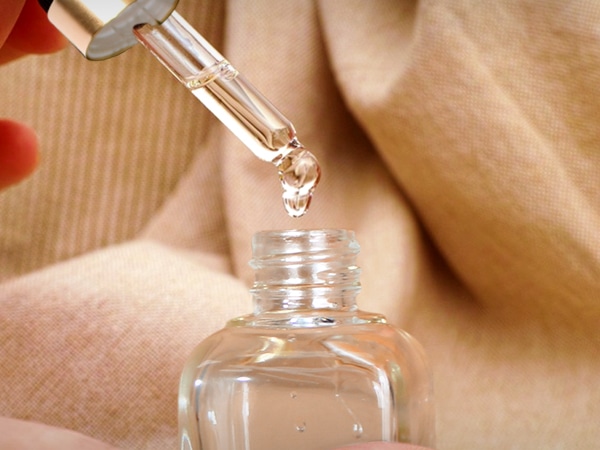 A person using one of glass eye dropper bottles to dispense liquid