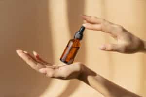 Amber glass serum bottle with a dropper held in two hands