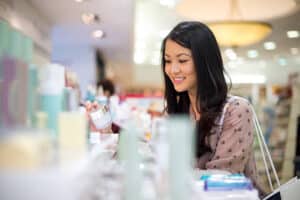 Smiling woman choosing cosmetic jars at a beauty store