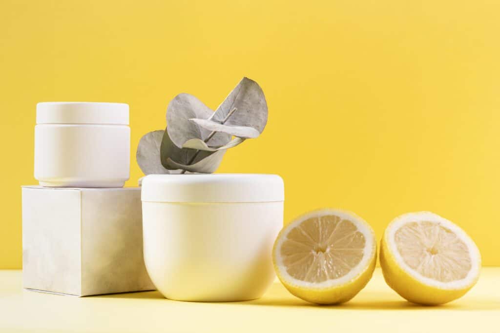 plastic cosmetics jars kept on a yellow backgound with leon slices  and a boxbeside 