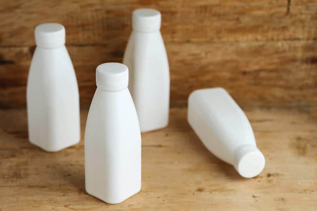 white plastic HDPE milk bottles on retro wooden table background